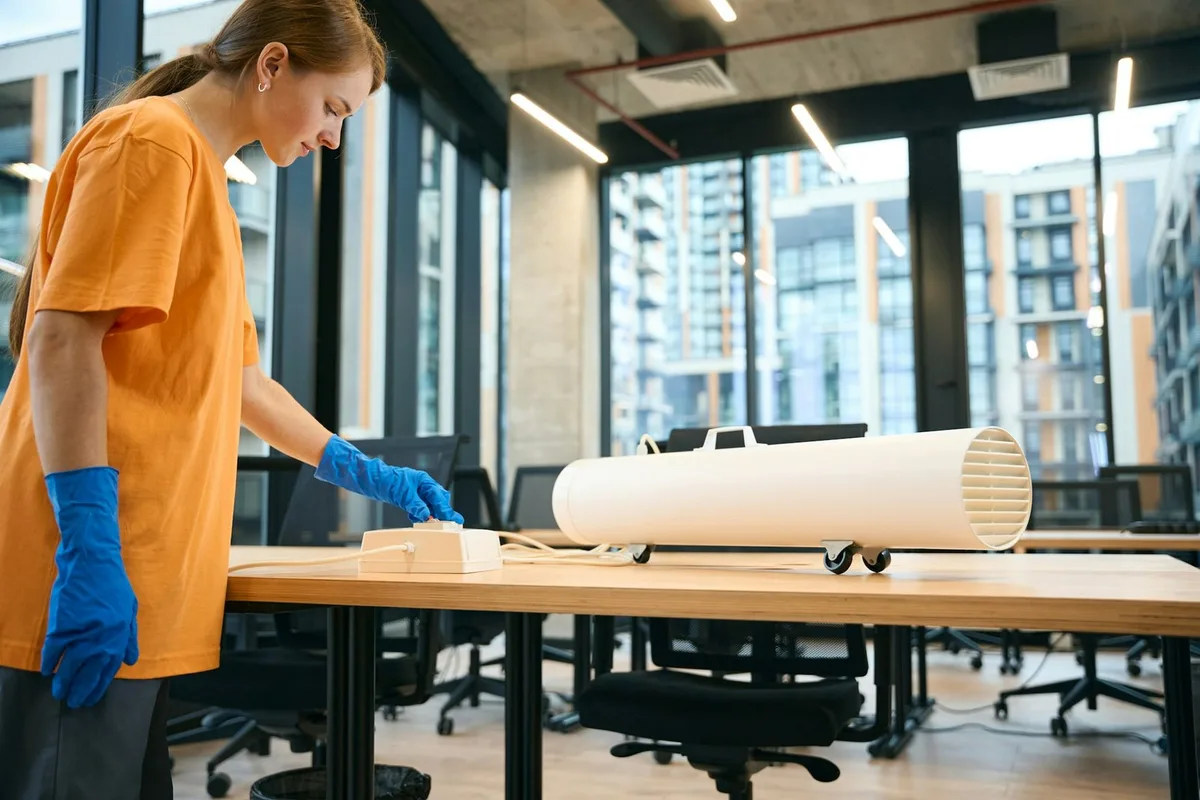 A cleaner setting up an ozone generator on an office table